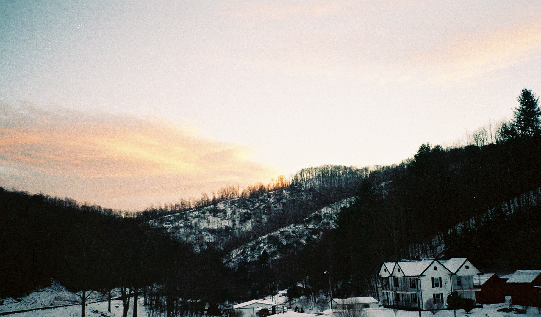 Winter golden sunset illuminating ridge silhouettes above a snow-covered valley town in the NC High Country