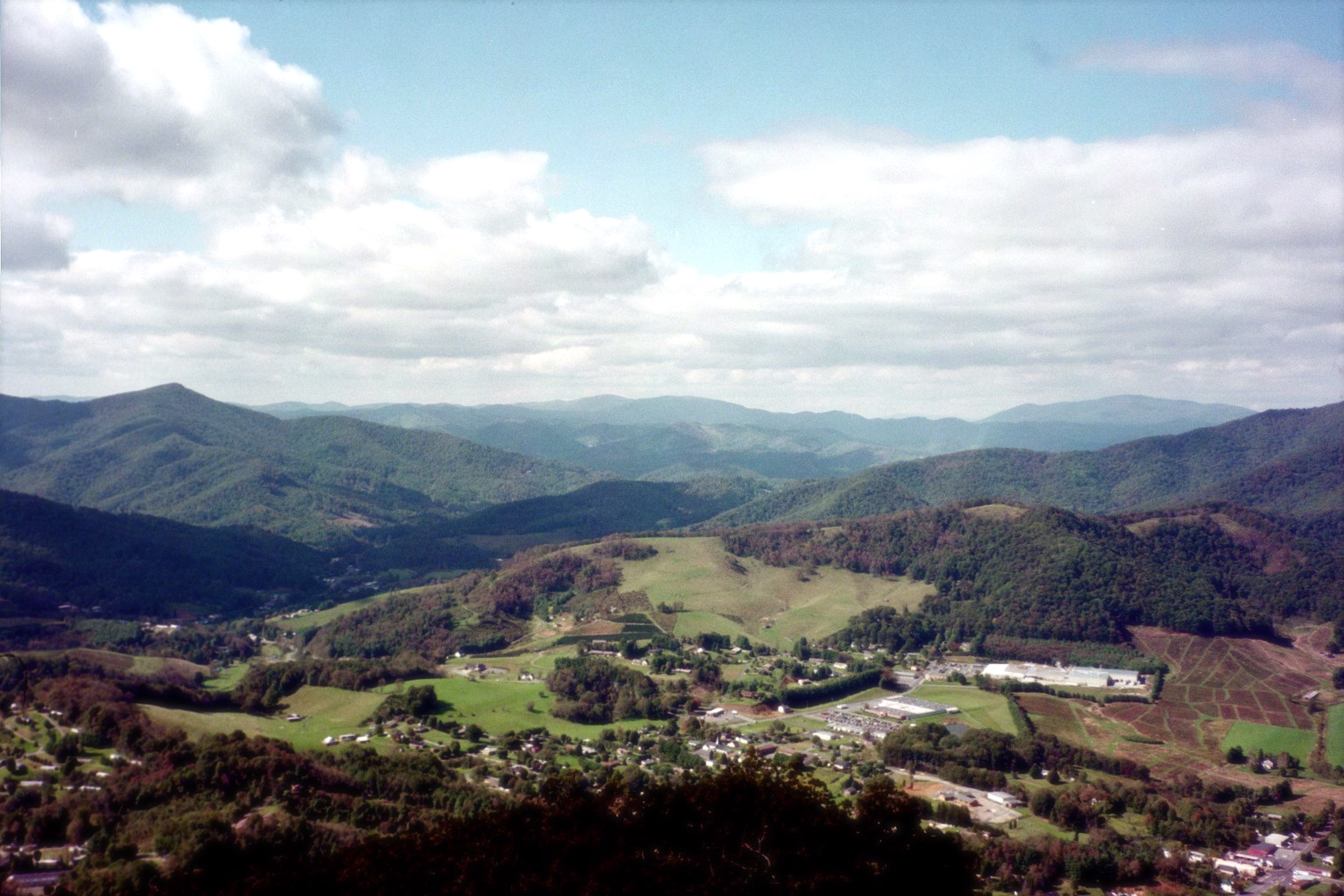 Aerial view of a High Country valley town with layered Blue Ridge ridgelines receding into atmospheric haze