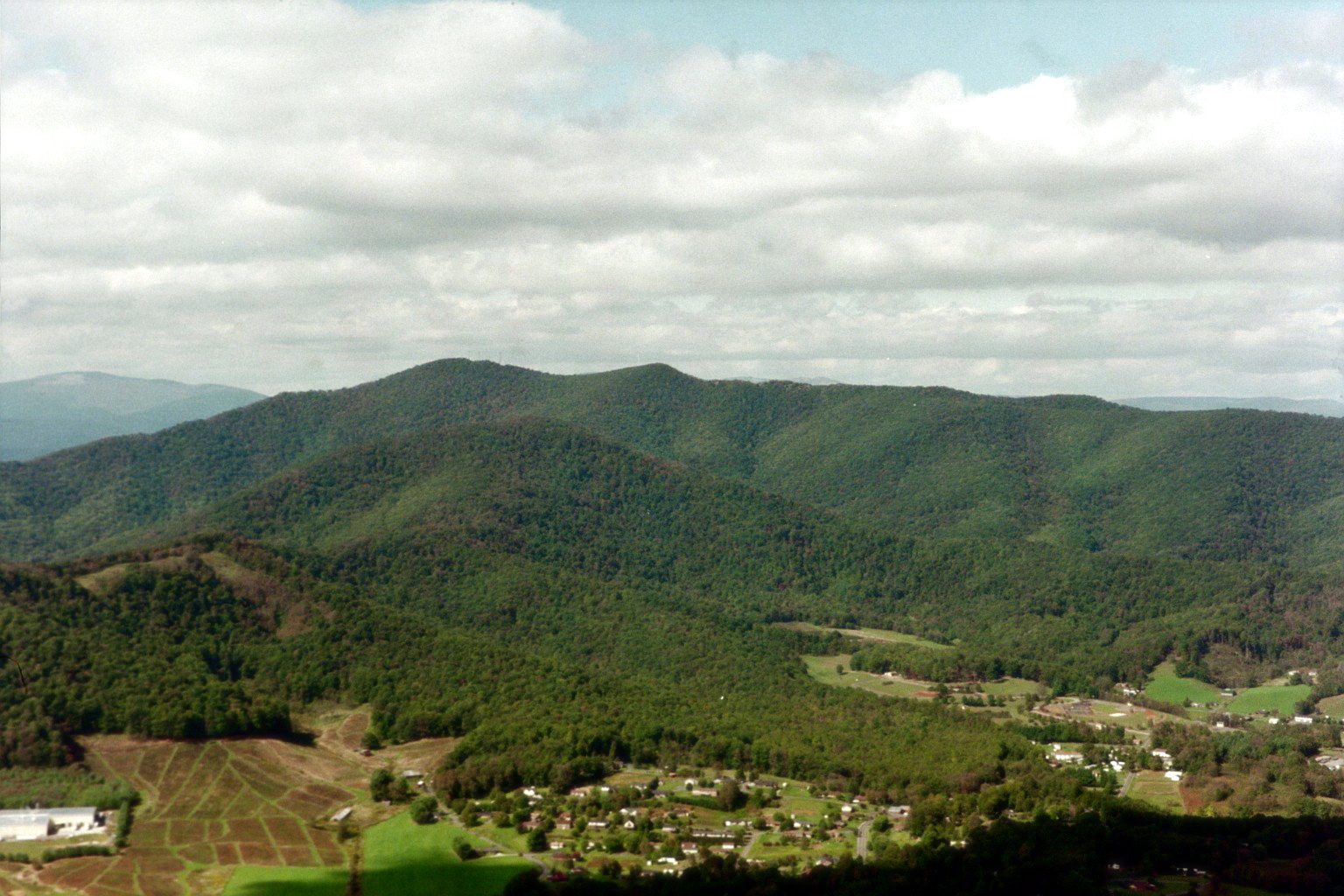 Aerial view of West Jefferson, NC with green farmland, downtown grid, and layered Blue Ridge ridgelines
