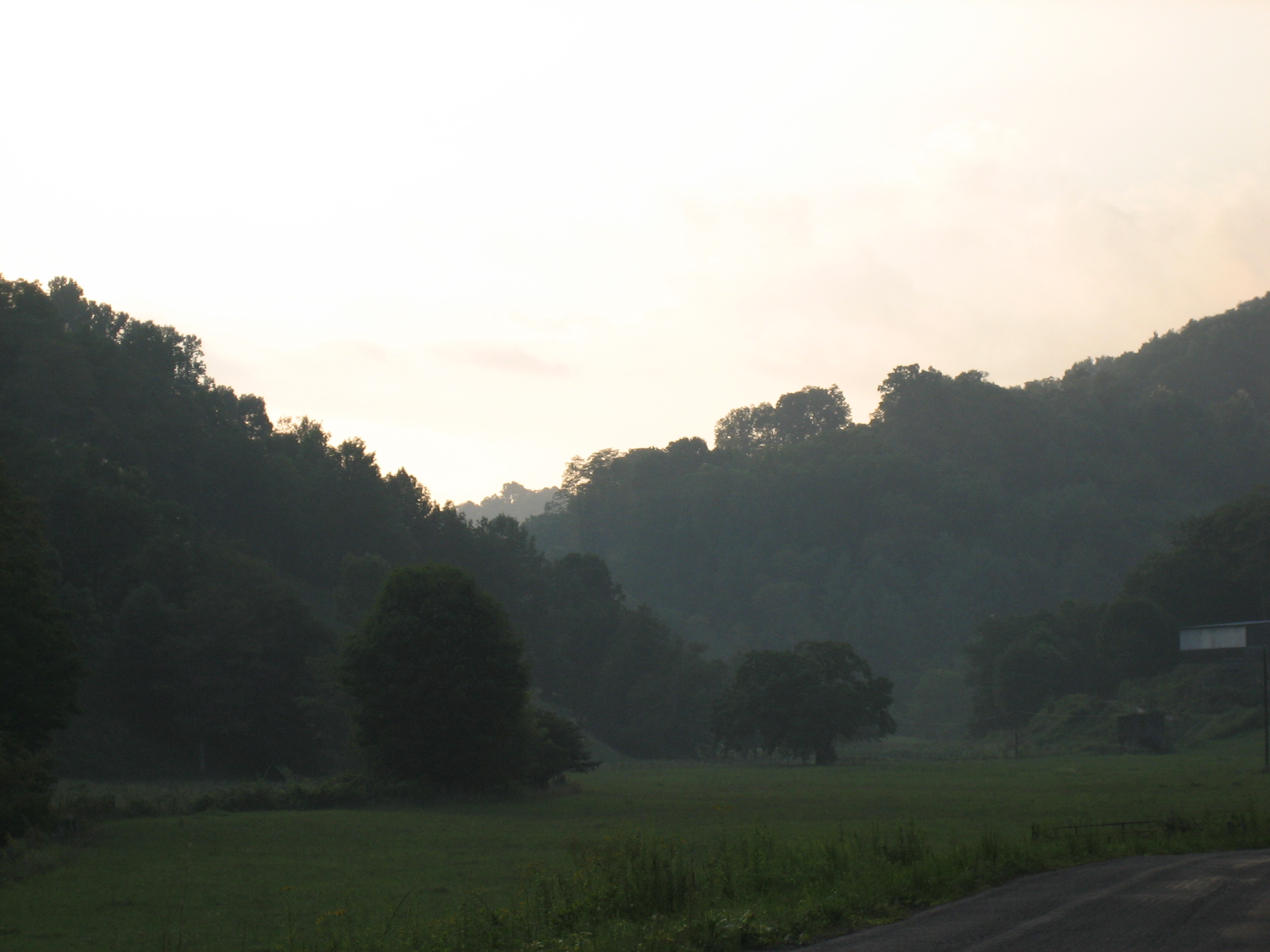 Morning valley fog lit by warm golden light with forested ridgelines rising above the mist in the NC High Country