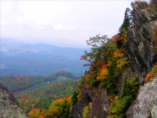 Autumn ridgeline layers viewed from a rocky cliff outcrop with orange and red foliage in the NC High Country