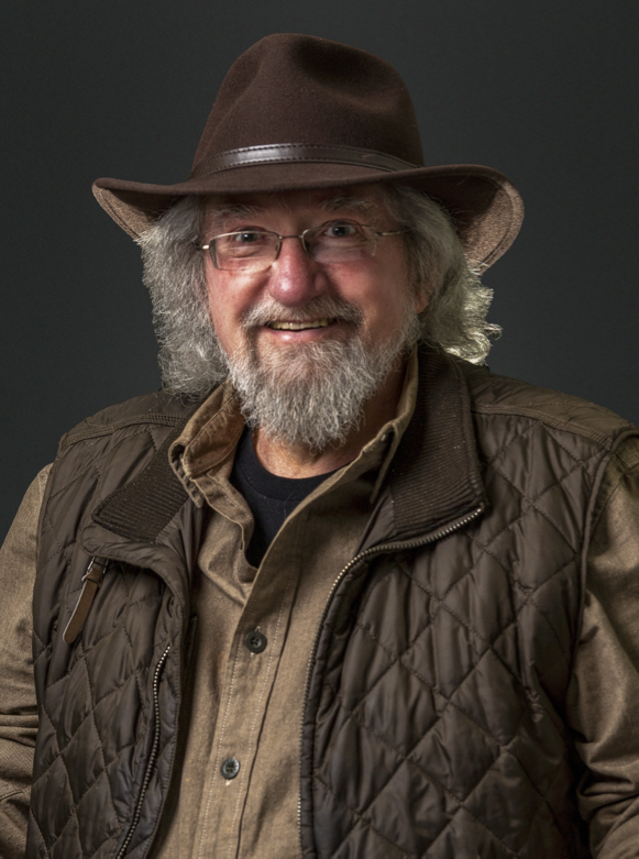 John Wheeler outdoors in the NC High Country mountains, wearing hat and vest